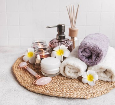 Spa seti, temel yağ, masaj tuzu, mum ve gri beton arka planda Frangipani çiçekleri