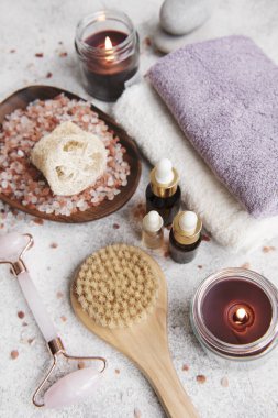 Güzel bir spa rahatlama konsepti. Vücut masajı için fırça, havlular, mumlar ve gri taş arka planda deniz tuzu