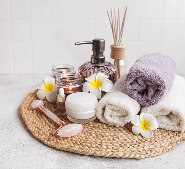 Spa seti, temel yağ, masaj tuzu, mum ve gri beton arka planda Frangipani çiçekleri