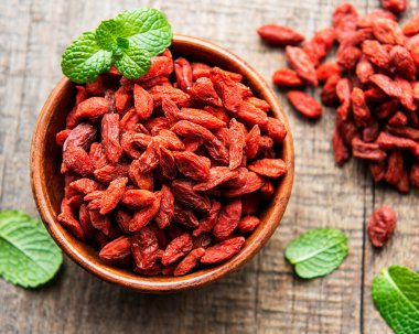 Sağlıklı beslenmek için kuru kırmızı goji üzümleri eski ahşap arka planda.