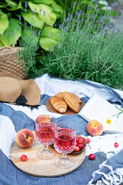 Lavanta tarlalarında piknik. Bardakta gül şarabı, battaniyede kiraz ve hasır şapka