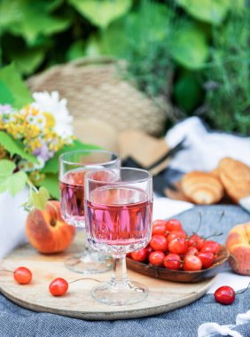 Lavanta tarlalarında piknik. Bardakta gül şarabı, battaniyede kiraz ve hasır şapka