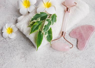 Güzel bir spa rahatlama konsepti. Havlu, yeşim taşlı silindir ve gri taşlı arka planda Frangipani çiçekleri.