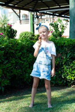 Küçük kız dışarıda çikolatalı dondurma yiyor.