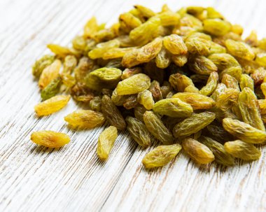 Beyaz ahşap arka planda yeşil kuru üzümler.