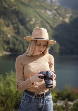 Dağın tepesinde elinde dijital fotoğraf makinesiyle duran fotoğrafçı turist. Yürüyüşçü fotoğraf çekiyor, kız doğanın tadını çıkarıyor gezide panoramik manzara, rahatlama ve tatil konsepti.