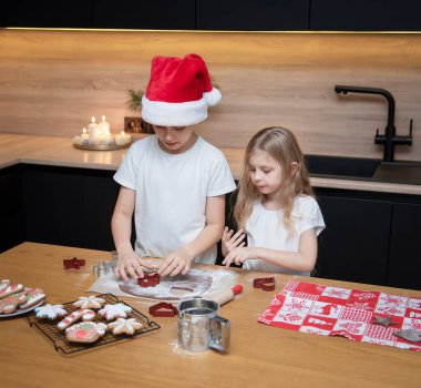 Noel tatiline hazırlanıyorum. Çocuklar - bir erkek ve bir kız mutfakta zencefilli ekmek hazırlıyorlar.