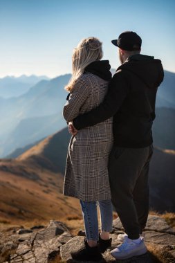 Genç mutlu çift dağlarda yürüyüş yaparken mola veriyor.