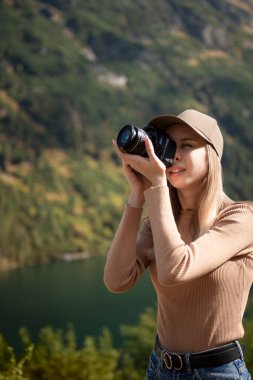 Dağın tepesinde elinde dijital fotoğraf makinesiyle duran fotoğrafçı turist. Yürüyüşçü fotoğraf çekiyor, kız doğanın tadını çıkarıyor gezide panoramik manzara, rahatlama ve tatil konsepti.