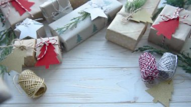 Kahverengi kağıda sarılmış Noel hediyeleri. Kadın eli masaya bir hediye koyar.