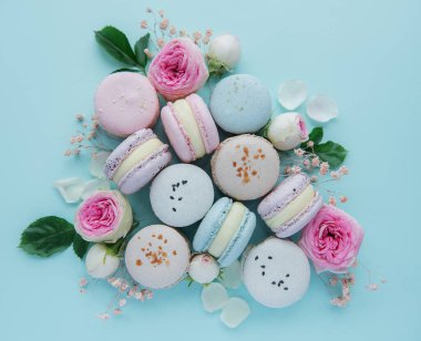 Mavi arka planda güzel gülleri olan lezzetli badem kurabiyeleri.