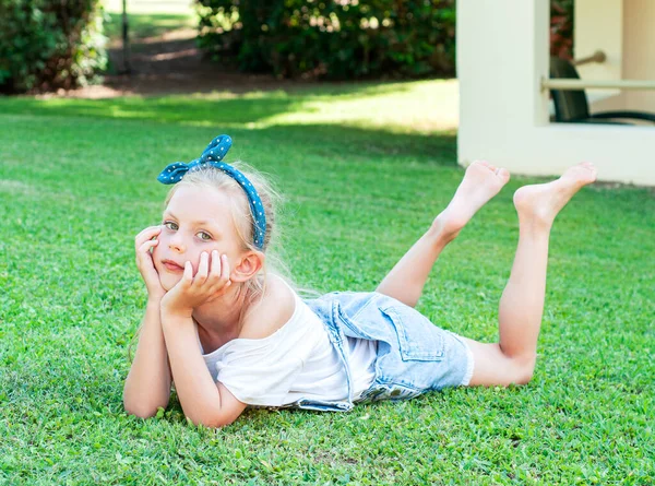 Cheerful Little Girl Denim Jumpsuit Lying Green Grass — Stock Photo, Image