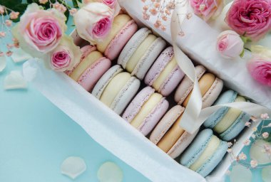 Lezzetli renkli badem kurabiyesi ve gül çiçekli bir kutu.