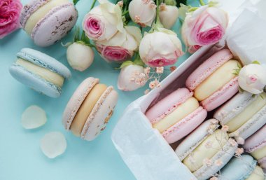 Lezzetli renkli badem kurabiyesi ve gül çiçekli bir kutu.