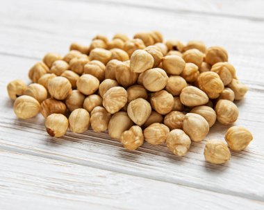 Beyaz ahşap arka planda soyulmuş fındıklar.