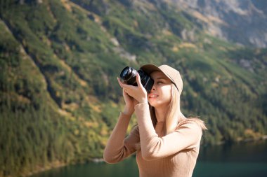 Dağın tepesinde elinde dijital fotoğraf makinesiyle duran fotoğrafçı turist. Yürüyüşçü fotoğraf çekiyor, kız doğanın tadını çıkarıyor gezide panoramik manzara, rahatlama ve tatil konsepti.