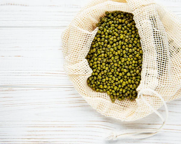 Raw mung beans in the cotton bag on a old wooden background