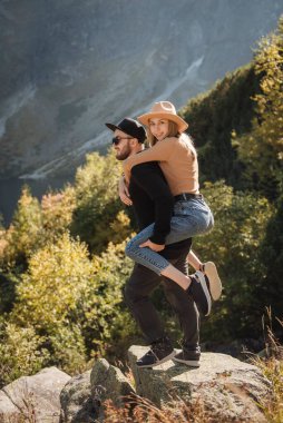 Dağlarda yürüyüp manzaranın tadını çıkaran mutlu bir çift turist. Erkek kadını kaldırır. Gezginler iyi eğlenceler.