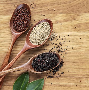Ahşap arka planda kırmızı, siyah ve beyaz kinoa tohumları