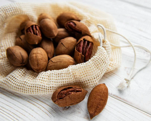 Pecan nuts in cotton bag on a wooden table