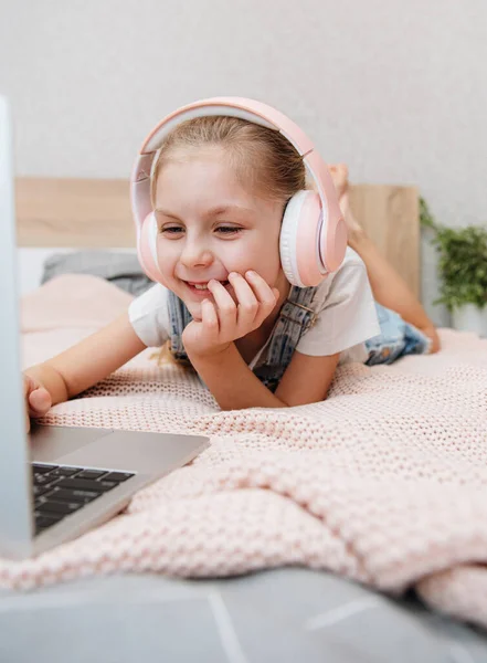 Hymyilevä Onnellinen Pieni Lapsi Tyttö Käyttää Kannettavaa Tietokonetta Langattomissa Kuulokkeissa — kuvapankkivalokuva