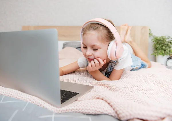 Hymyilevä Onnellinen Pieni Lapsi Tyttö Käyttää Kannettavaa Tietokonetta Langattomissa Kuulokkeissa — kuvapankkivalokuva