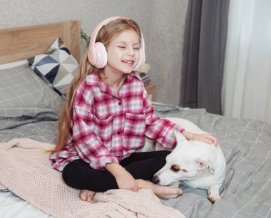 Kız ve köpek kanepede oturmuş, akıllı telefonuyla müzik dinliyor..