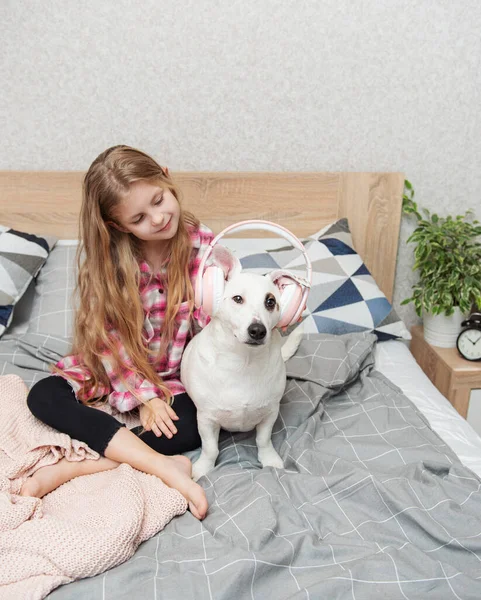 子供の娘と犬 小さな女の子置くヘッドフォンオン彼女の犬 — ストック写真