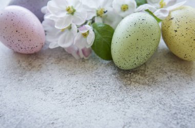 Beton zeminde renkli paskalya yumurtaları ve bahar çiçeklerinin üst görüntüsü