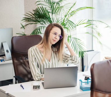 Ofisindeki bilgisayarda çalışan genç bir kadın.