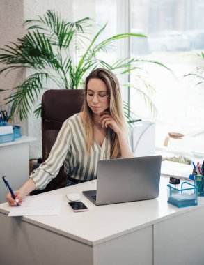 Ofisindeki bilgisayarda çalışan genç bir kadın.