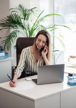 Ofisindeki bilgisayarda çalışan genç bir kadın.