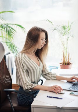 Ofisindeki bilgisayarda çalışan genç bir kadın.