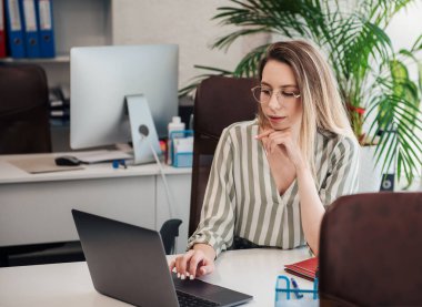 Ofisindeki bilgisayarda çalışan genç bir kadın.