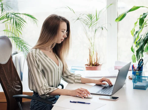 Ofisindeki bilgisayarda çalışan genç bir kadın.