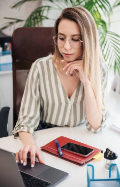 Ofisindeki bilgisayarda çalışan genç bir kadın.