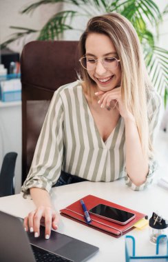 Ofisindeki bilgisayarda çalışan genç bir kadın.