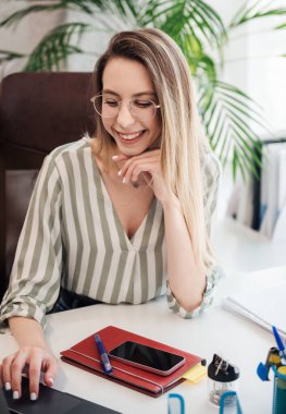 Ofisindeki bilgisayarda çalışan genç bir kadın.
