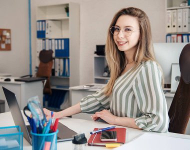 Ofisindeki bilgisayarda çalışan genç bir kadın.