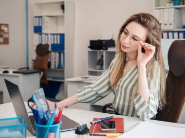 Ofisindeki bilgisayarda çalışan genç bir kadın.