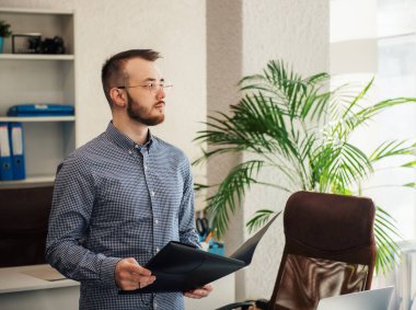 Ofiste dizüstü bilgisayarıyla çalışan gömlekli genç bir iş adamı.
