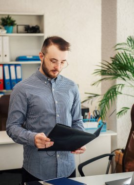 Ofiste dizüstü bilgisayarıyla çalışan gömlekli genç bir iş adamı.