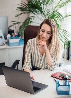 Ofisindeki bilgisayarda çalışan genç bir kadın.