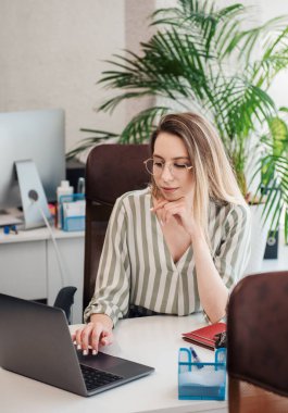 Ofisindeki bilgisayarda çalışan genç bir kadın.