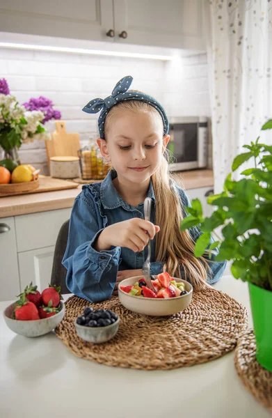 Healthy food at home. Cute little girl eats fruit salad