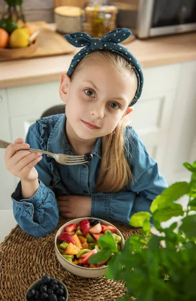 Healthy food at home. Cute little girl eats fruit salad