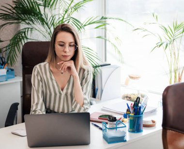 Ofisindeki bilgisayarda çalışan genç bir kadın.