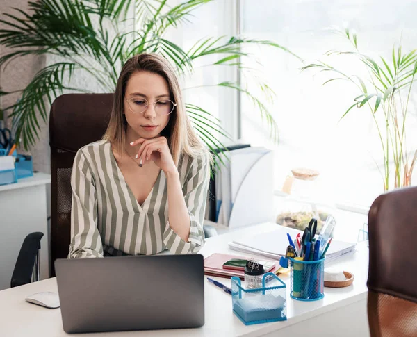 Ofisindeki bilgisayarda çalışan genç bir kadın.