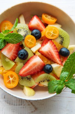 Tahta arka planda bir kasede sağlıklı taze meyve salatası.