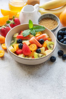 Beton arka planda bir kasede sağlıklı taze meyve salatası.